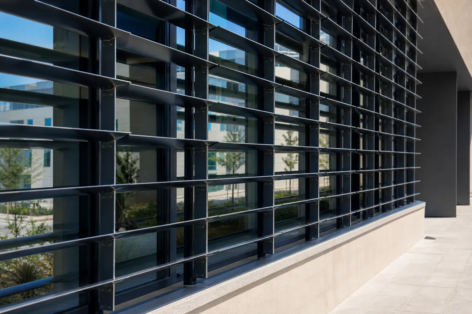 Brise-soleil orientable en aluminium posé devant une façade vitrée, lames inclinées filtrant le soleil
