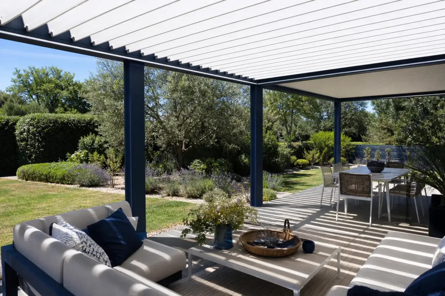 Pergola bioclimatique aux lames orientables au-dessus d’une terrasse aménagée, ombre projetée au sol